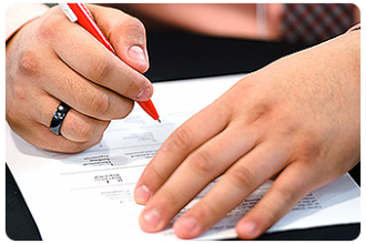 Hands holding a pen filling out a form