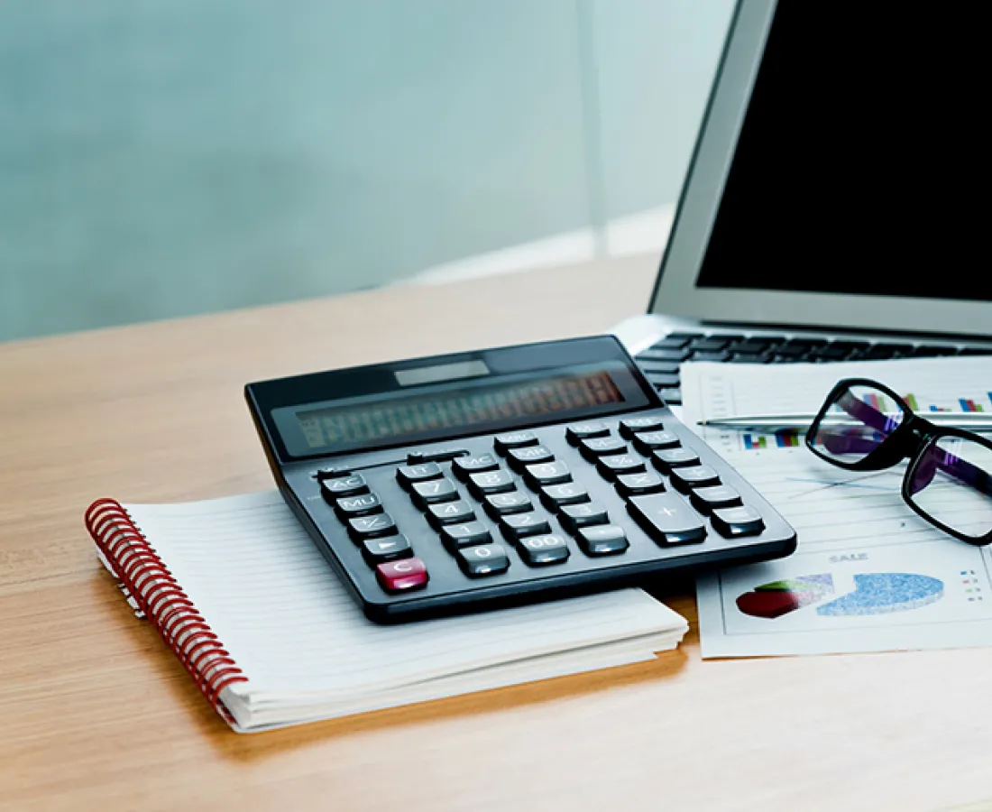 calculator laptop and other office supplies on desk