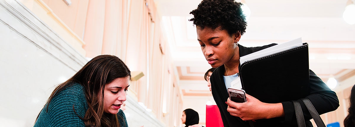 Two students look over resources at an OCM event