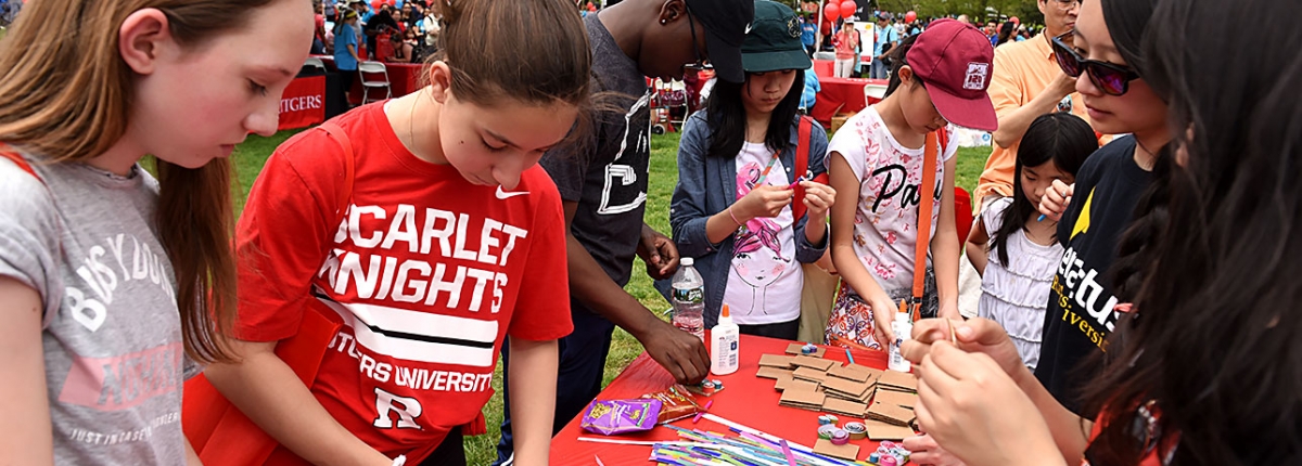 Students and Rutgers Day attendees interact at a crafts table