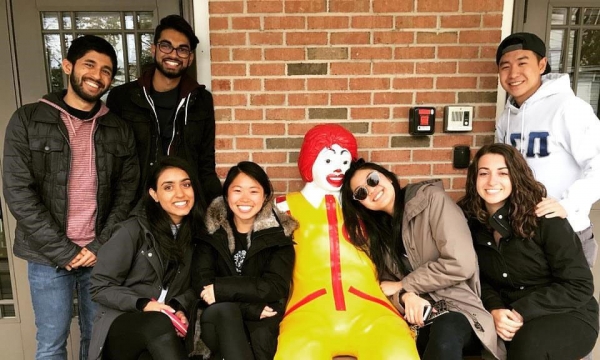 Members of Delta Sigma Pi posing on a bench with a fast food mascot