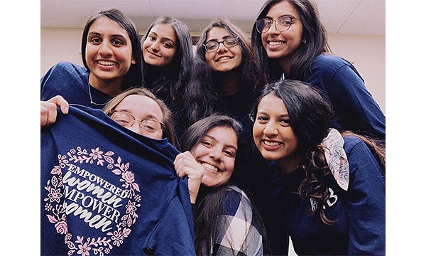 Members pose with a women empowerment t-shirt
